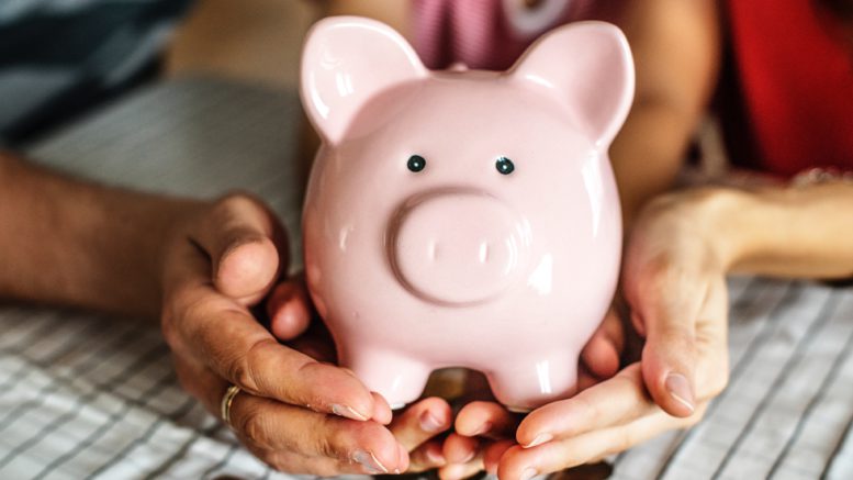 Photo of two people holding a piggy bank