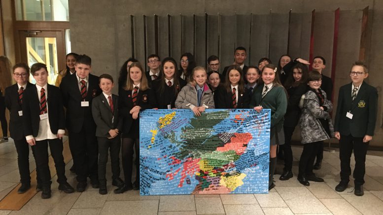 School pupils holding painted map of Scotland with UN Convention on the Rights of the Child inscribed on it