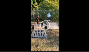 Still from video of two young children playing on wooden palates