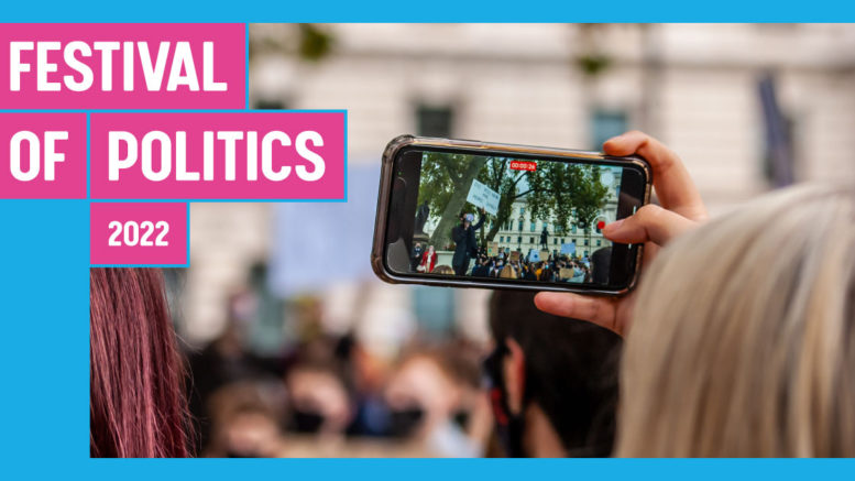Festival of Politics banner with person recording demonstration on their phone